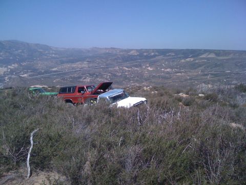 1978 Ford Bronco - Two trucks sit in a dry, brushy landscape under a clear blue sky.