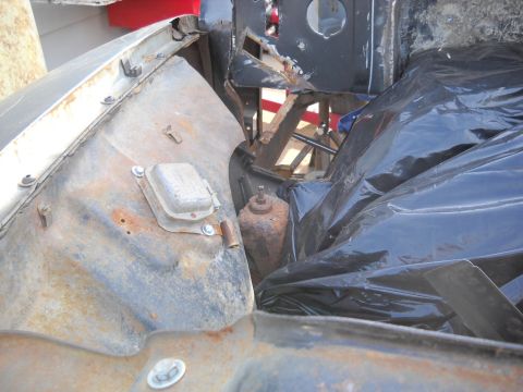 1954 Ford F-100 - The engine bay of a 1954 Ford F-100 shows significant rust and is partially covered by black plastic sheeting.