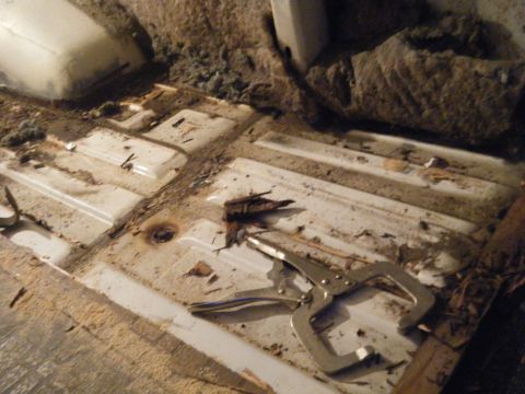 1981 Ford E350 - Interior floor of a van, showing debris and a locking plier on the metal flooring.