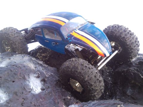1989 Ford Bronco - A blue RC car with racing stripes navigates a rocky terrain.