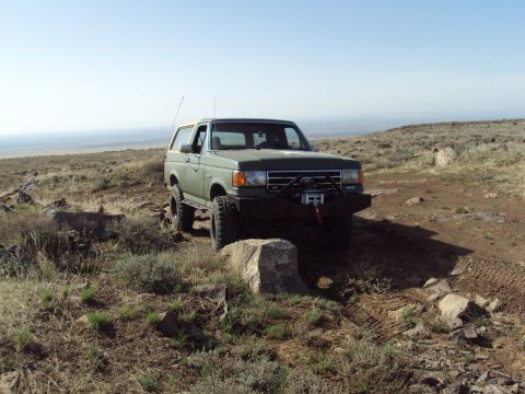 1989 Ford Bronco - A modified Ford Bronco navigates a rocky, off-road trail under a clear sky.