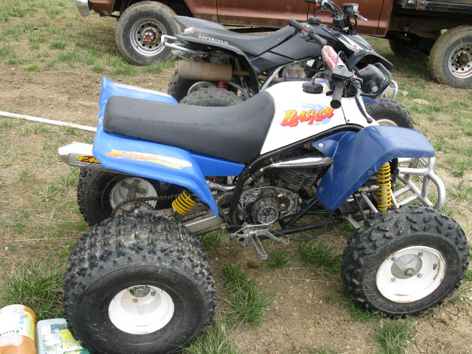 Blue and white all-terrain vehicle with yellow shocks and knobby tires, parked outdoors