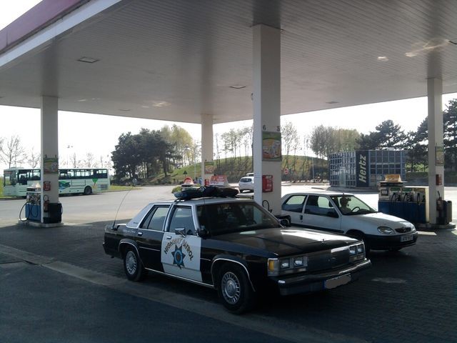 Black and white police car, 1991 Ford Crown Victoria, parked at gas station