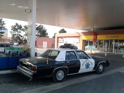 1991 Ford Crown Victoria - Police car refueling at a gas station with a "Tigermarket" store in the background.