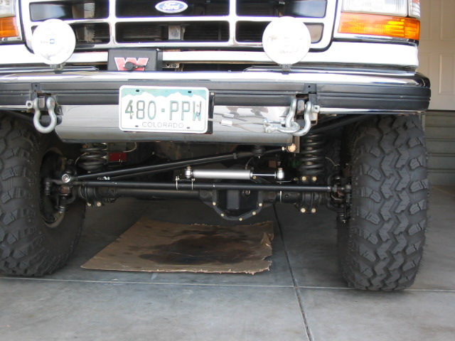 Front axle and black steering linkage under a lifted Ford truck with Colorado plate 480-PPW