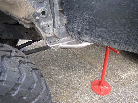1996 Ford Bronco - A vehicle's undercarriage, showing modifications and a red jack supporting the frame.