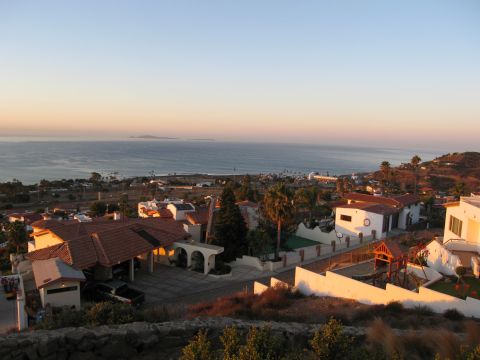 1986 Ford Bronco - A scenic view of a coastal town overlooking the ocean at sunset, with houses and palm trees visible.