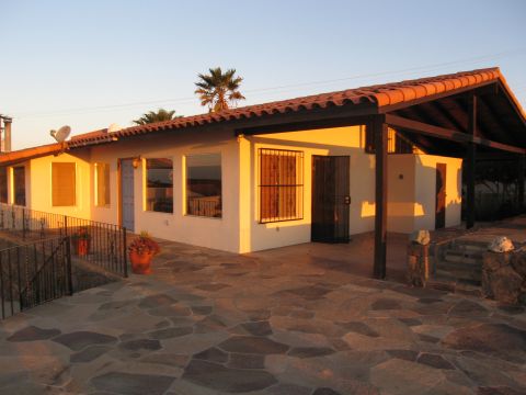 1986 Ford Bronco - A house with a tiled roof and a stone patio is bathed in the warm light of sunset.