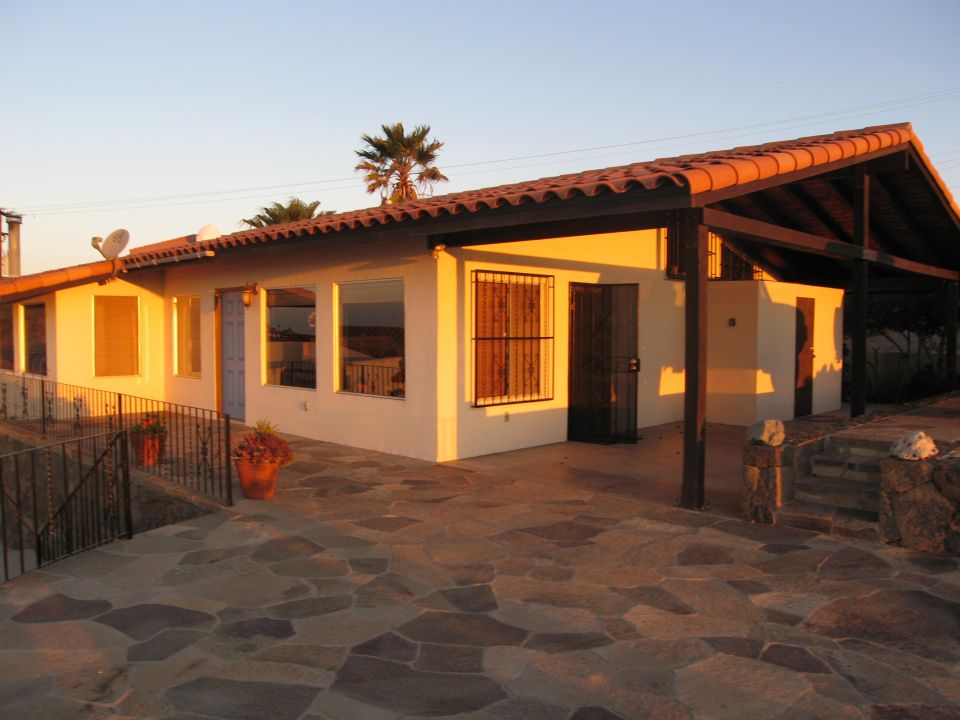 House with tiled roof and stone patio at sunset