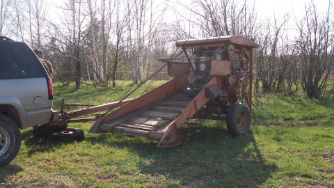 2000 Chevrolet Tahoe - A silver SUV is seen towing an orange agricultural implement through a grassy field with trees in the background.
