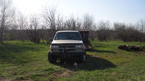 2000 Chevrolet Tahoe - A lifted Chevrolet K1500 pickup truck is parked in a field under a clear sky.