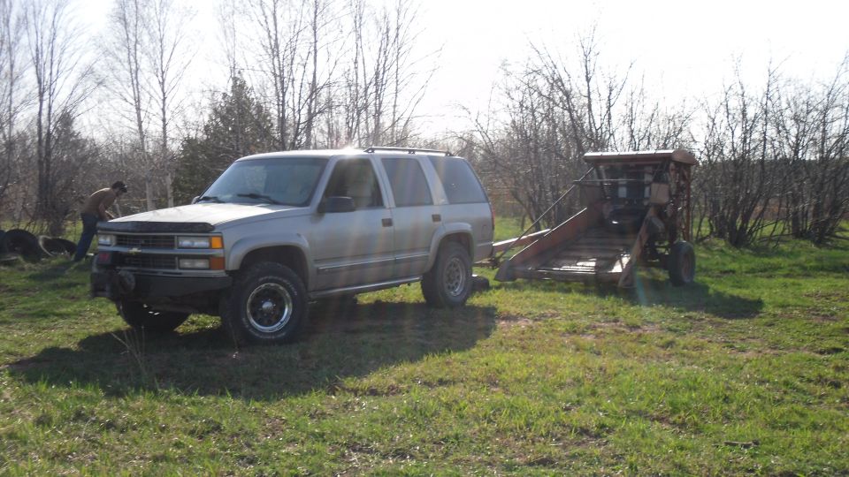 Silver SUV with a winch, towing a red trailer with machinery