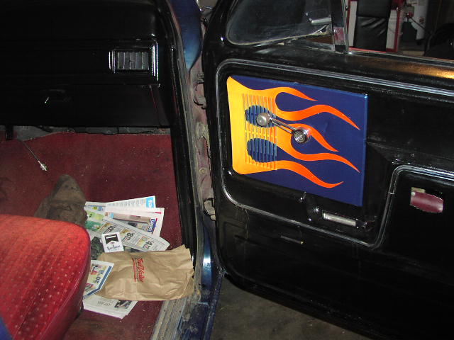 Custom blue door panel with orange flames and chrome crank on a truck interior