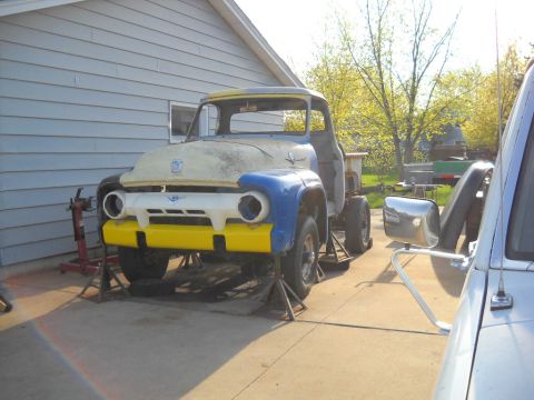 1954 Ford F-100 - A partially restored 1953 Ford F-100 truck is elevated on jack stands in a driveway.