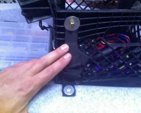 1953 Ford Mainline - A hand secures a strap to a black basket containing wires and other items.