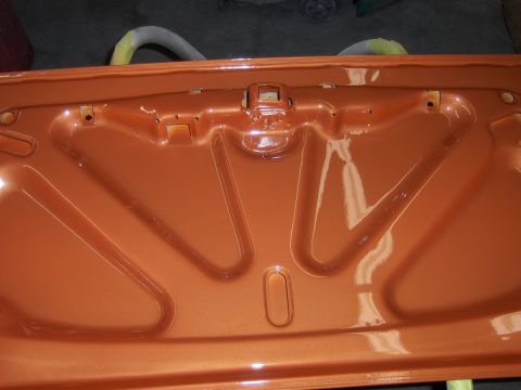 1980 Chevrolet Camaro - The inside of a car trunk, freshly painted orange, shows structural bracing and the latch assembly.