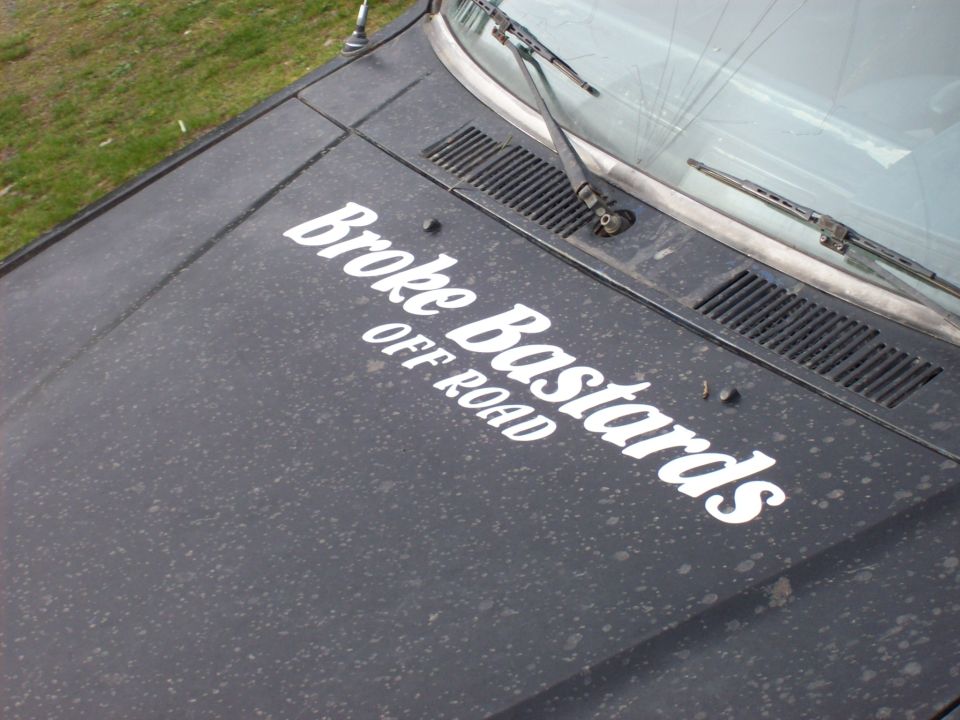 Dusty truck hood with "Broke Bastards OFF ROAD" decals. Windshield wipers visible
