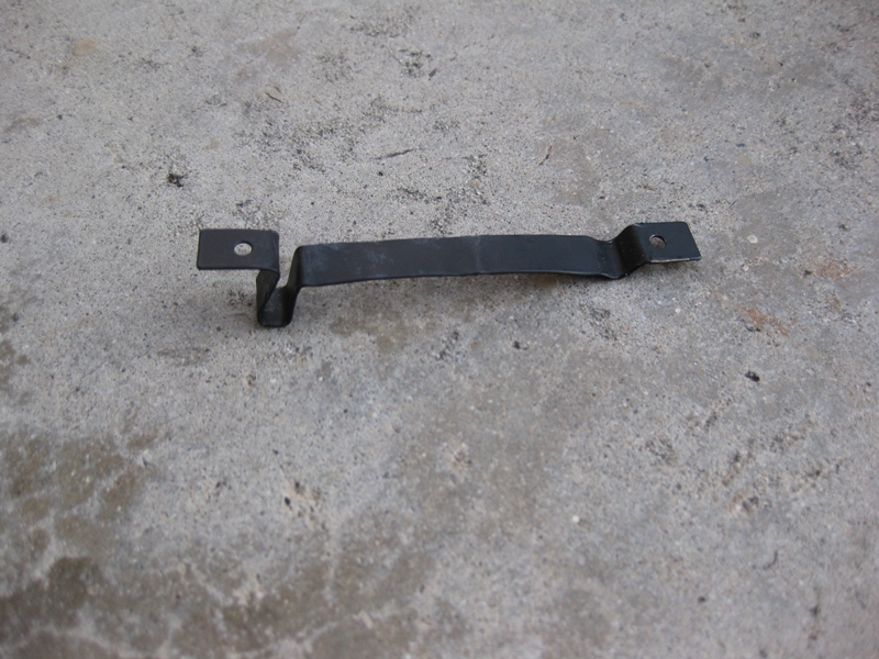 black metal bracket with two mounting holes sits on a concrete surface