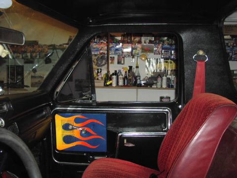 1981 Ford Bronco - The interior of a truck features a custom flame decal on the door panel and a cluttered shelf visible through the window.