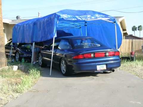 1995 Ford Probe - Blue 1995 Ford Probe parked under a blue tarp, with another vehicle visible to the left.