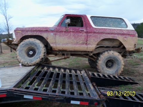 1978 Ford Bronco - A heavily modified 1978 Ford Bronco is shown covered in mud, positioned on a trailer ramp.