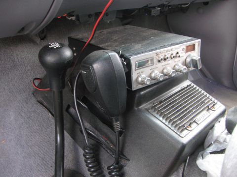 1996 Ford C-350 (Centurion Conversions) - Close-up of a CB radio and its microphone, positioned next to a vehicle's gear shifter.