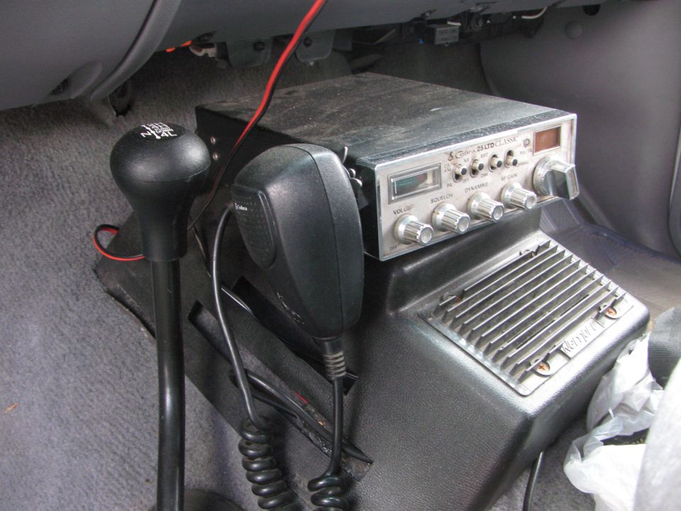 CB radio and microphone next to a gear shifter inside a vehicle