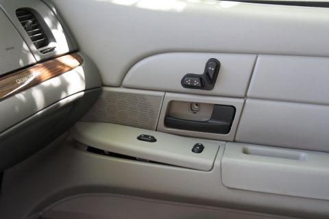 2007 Ford Crown Victoria - Close-up of a car's interior door panel, showing power seat controls and window switches.