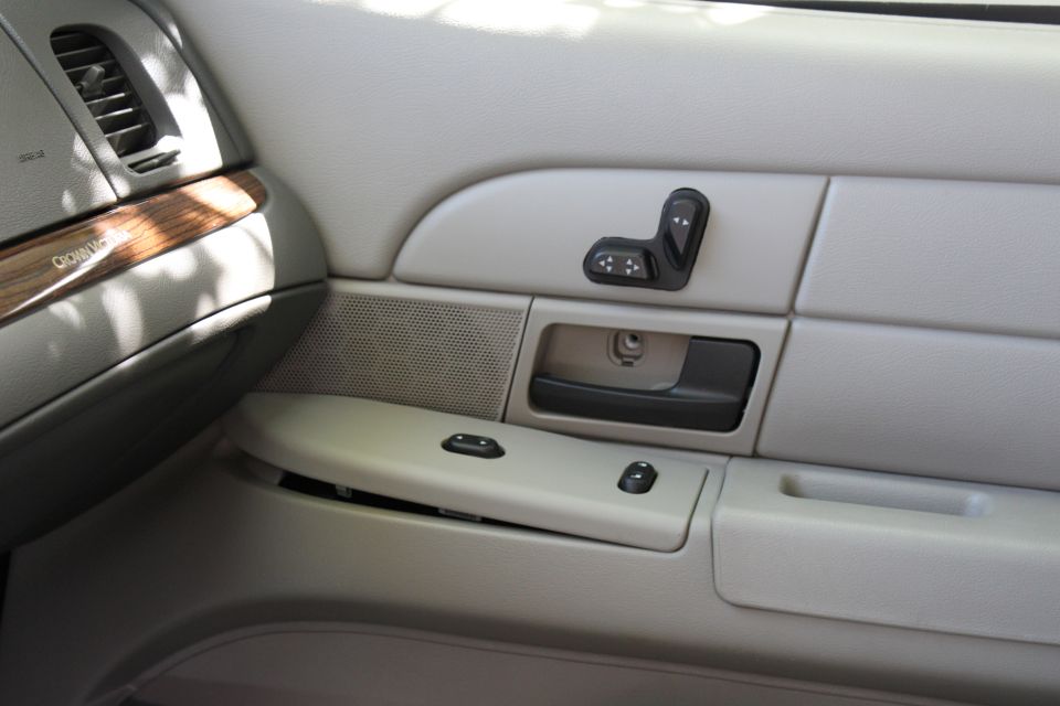 Tan Crown Victoria door panel with power seat switch and dash wood trim reading CROWN VIC
