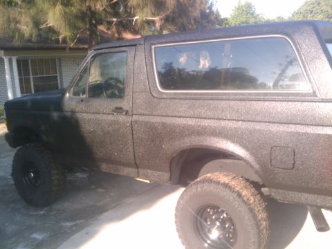 1993 Ford Bronco - Side view of a textured black Ford Bronco, likely from the early 1990s.