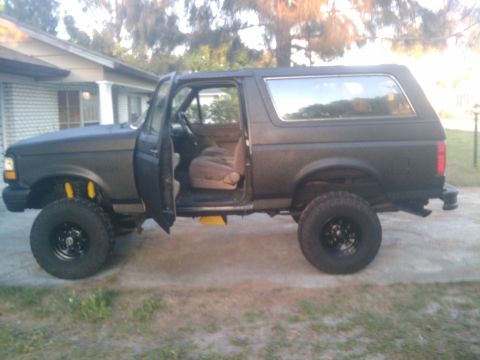 1993 Ford Bronco - This lifted Ford Bronco is parked outside a house with its doors open.
