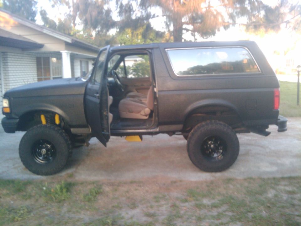Lifted black Ford Bronco with doors open, parked in a driveway