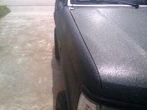 1993 Ford Bronco - Side view of a 1993 Ford Bronco with a textured black paint finish on the fender.