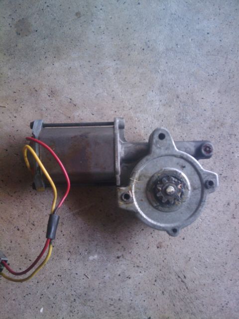 1993 Ford Bronco - A window motor with attached wiring lies on a textured concrete floor.