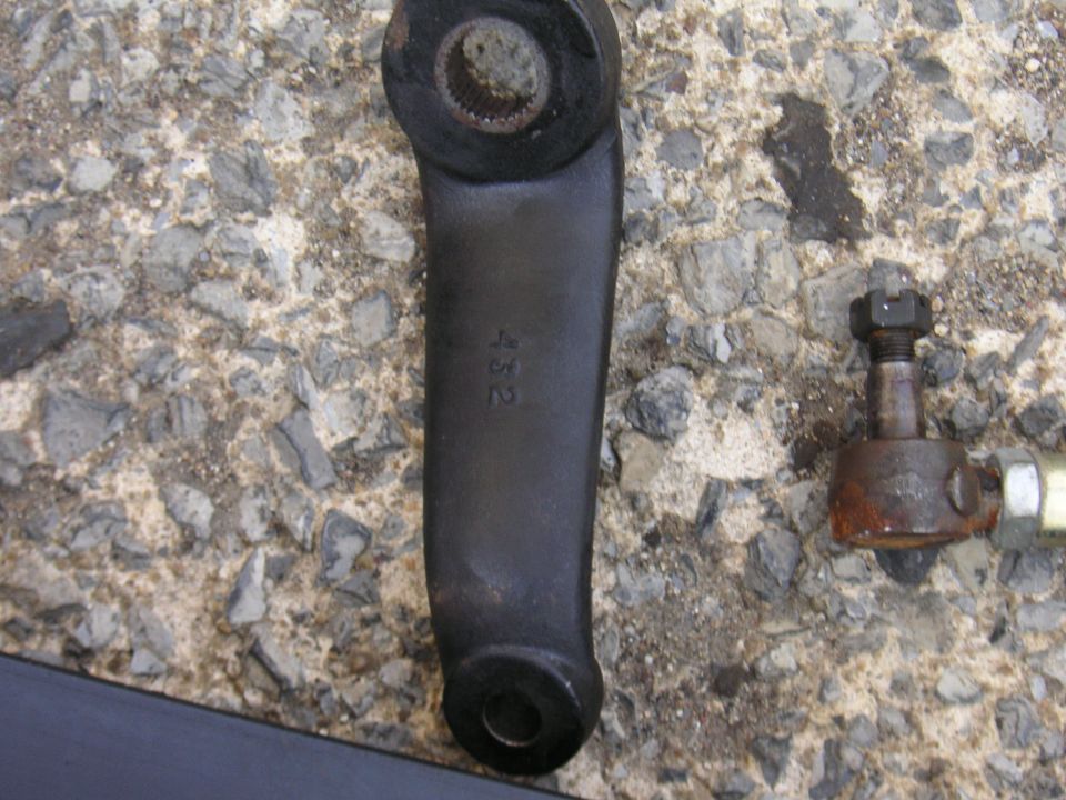 Black steering arm with "432" stamped on it, next to a rusty tie rod end