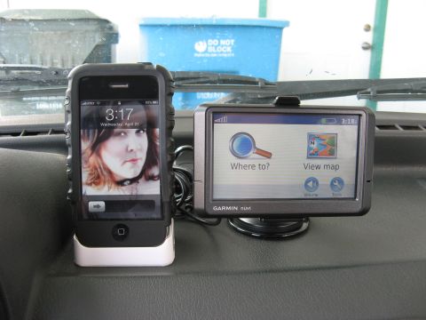 1991 Ford Festiva - Dashboard view with an iPhone and a Garmin GPS device. The iPhone displays a lock screen with a woman's photo.