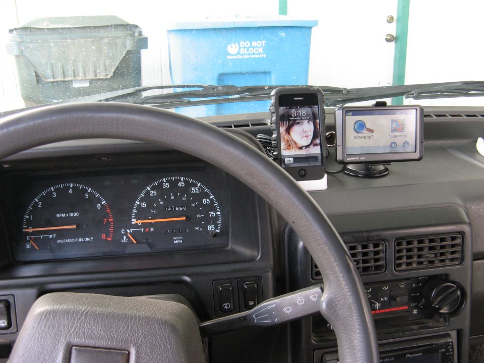 Car interior with dashboard, steering wheel, and mounted phone and GPS