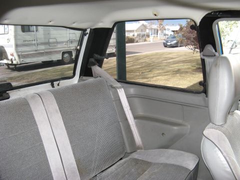 1991 Ford Festiva - View from the back seat of a car, looking out at a residential street with an RV parked on the side.