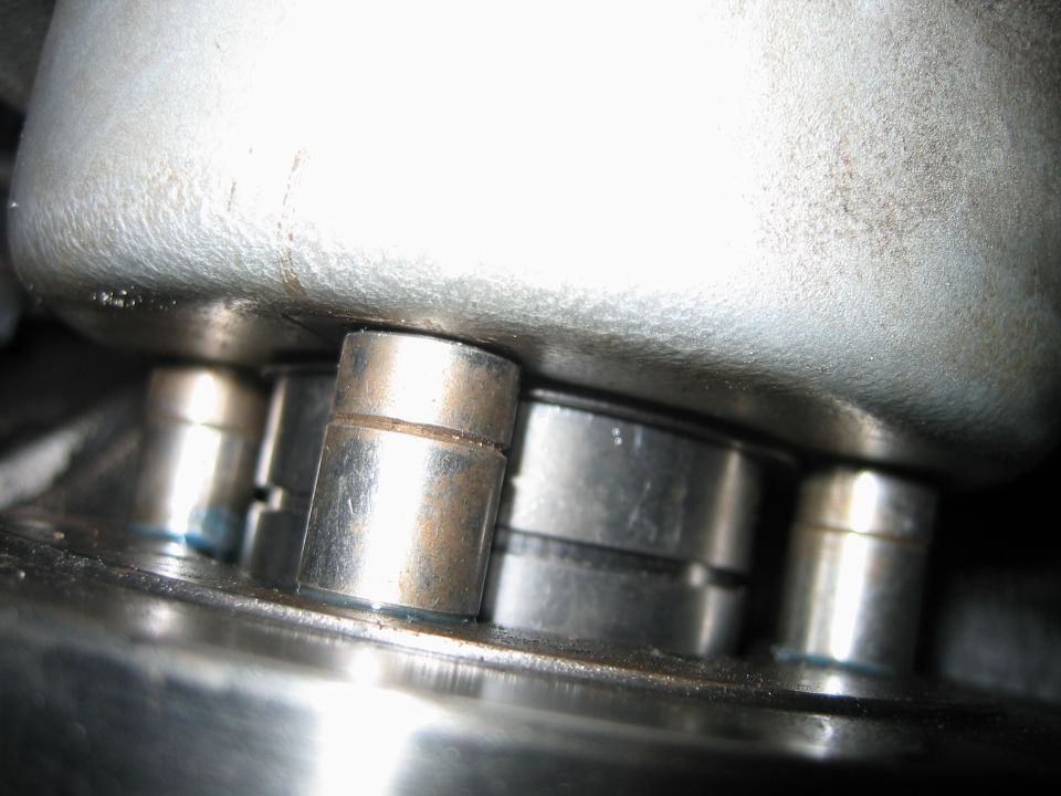 Macro close-up of steel pins between a polished flange and cast aluminum housing on a mechanical assembly