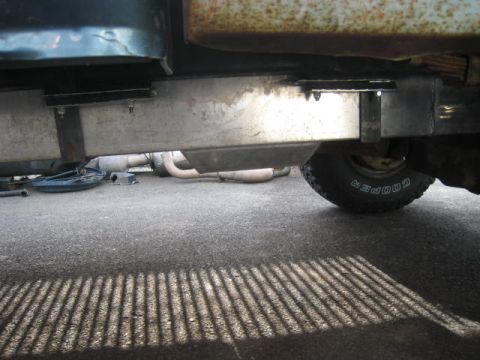 1976 Ford F-250 - The underside of a truck reveals a custom fuel tank and exhaust system, with a Cooper tire visible.