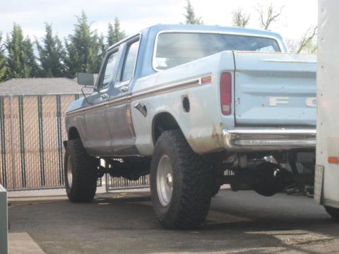 1976 Ford F-250 - Rear view of a lifted, light blue and white Ford F-250 truck with a chrome bumper and visible rear axle.