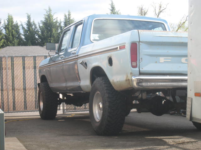 Light blue and white Ford F-250 truck, lifted, with chrome bumper and visible rear axle