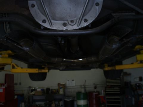 2002 Chevrolet Camaro - The underside of a vehicle is shown, focusing on the dual exhaust system and rear differential, likely in a repair shop.