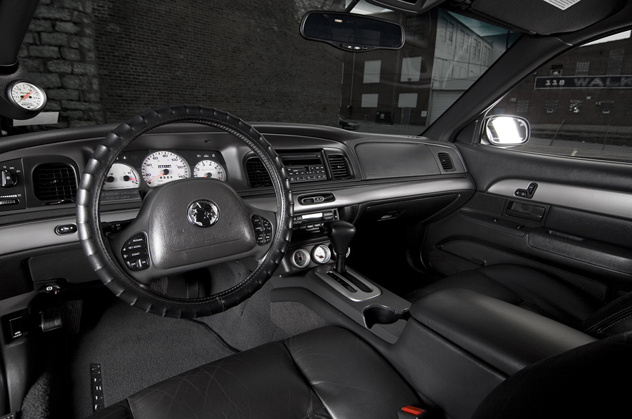 Black sedan interior, Mercury-badged wheel, white gauges, A-pillar boost gauge