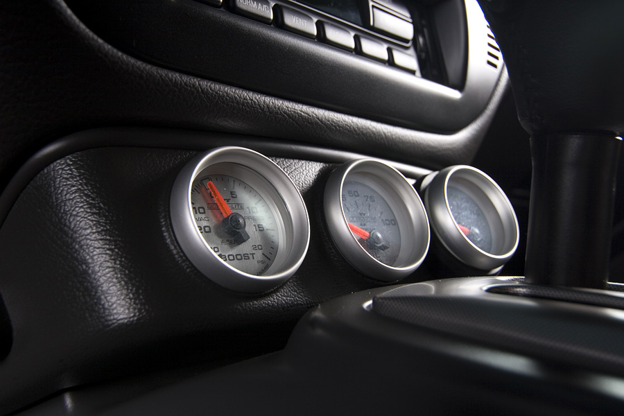 Three silver Auto Meter boost and pressure gauges in a black dash pod beside the shifter