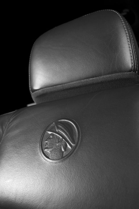2003 Mercury Marauder - Close-up of a black leather car seat the embossed Mercury emblem, likely from a 2003 Mercury Marauder.
