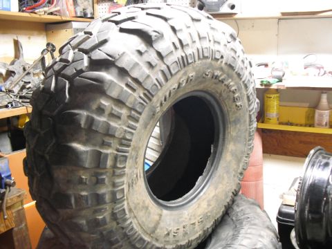 1991 Ford Bronco - A Super Swamper tire is shown in a cluttered garage, likely awaiting installation or repair.
