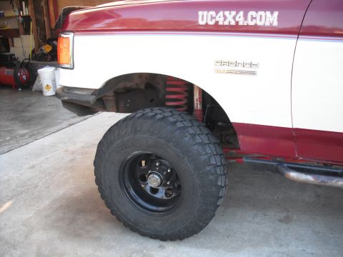 1991 Ford Bronco - Close-up of a 1991 Ford Bronco XLT's side, highlighting its off-road tire and fender, with a website decal visible on the body.