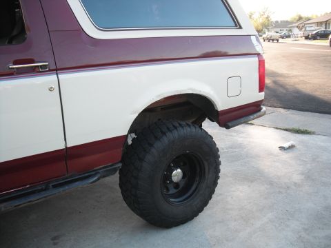 1991 Ford Bronco - The side profile of a two-tone Ford Bronco shows its large off-road tire and rear bumper.