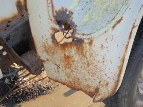 1954 Ford F-100 - This close-up shows significant rust damage on a vehicle's fender, with exposed metal and a hole.
